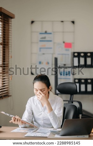 Asian business woman is stressed, bored, and overthinking from working on a tablet at the modern office.

