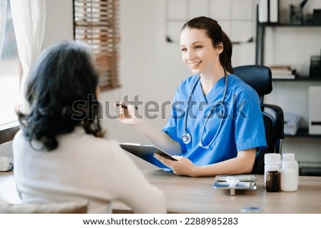 Asian Doctor and patient discussing something while sitting at the wood table . Medicine and health care concept. 
