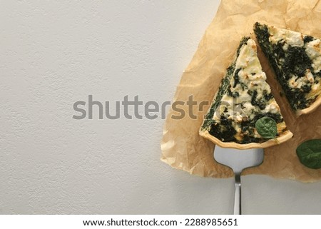 Delicious homemade spinach quiche on white table, top view. Space for text