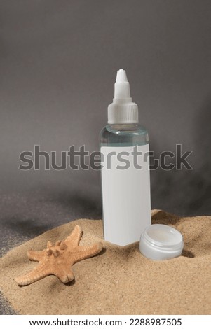 Cosmetic products and starfish on sand against grey background
