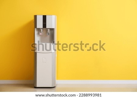 Modern water cooler near yellow wall Royalty-Free Stock Photo #2288993981