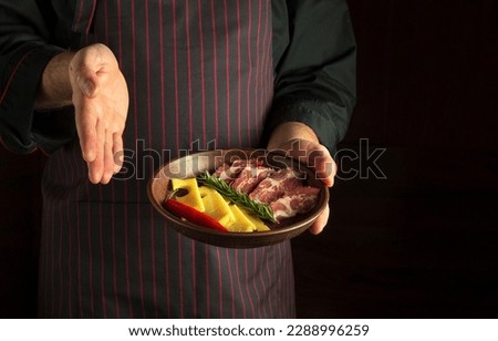 Chef presents a sliced steak with ham and cheese on a plate. The concept of serving dishes to order by a waiter with space for advertising on a dark background