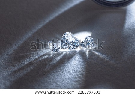 Three heart cut diamonds of different sizes on light background. Royalty-Free Stock Photo #2288997303