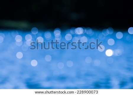 Blue bokeh on the water in black background