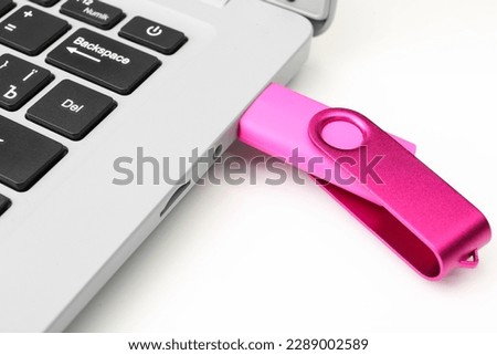 Laptop with pink USB flash drive isolated on white background