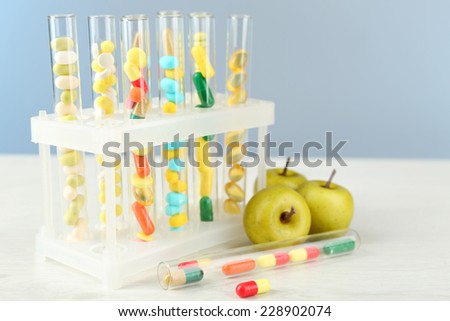 Different color drugs in test tubes and fruits, on wooden table, on color  background