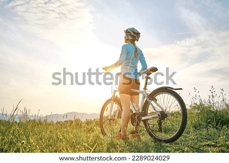 Cyclist Woman riding bike in helmets go in sports outdoors on sunny day a mountain in the forest. Silhouette female at sunset. Fresh air. Health care, authenticity, sense of balance and calmness. Royalty-Free Stock Photo #2289024029
