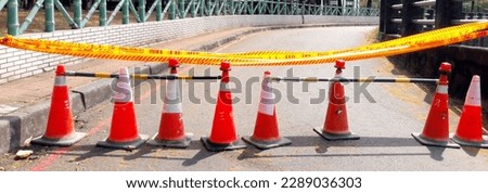 Close up of orange construction cones with yellow warning tape at road construction site in Taiwan before urban road repair and reconstruction is blocked. Shooting in the sun creates contrast. Royalty-Free Stock Photo #2289036303