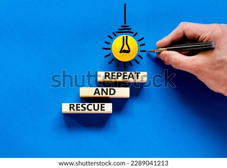 Rescue and repeat symbol. Concept words Rescue and repeat on wooden block on a beautiful blue table blue background. Light bulb icon. Businessman hand. Business rescue and repeat concept. Copy space.