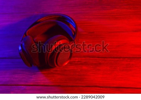 Black headphones on the wooden background. Neon lights, vintage style