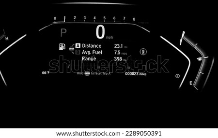Toned photo illuminated instrument panel dashboard on new car with very low milage at only 23 miles odometer, digital display of gauges and indicators, fuel level, engine temperature. Modern driving Royalty-Free Stock Photo #2289050391