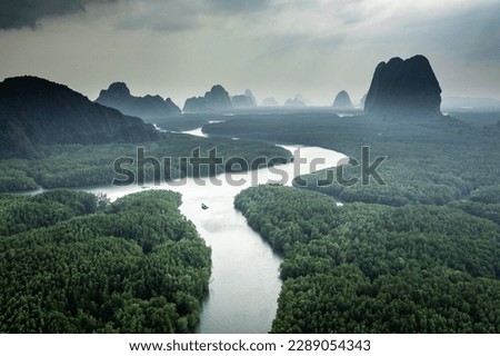 River and green forest in Thailand natural park, aerial view.  Beautiful natural scenery of river in southeast Asia tropical green forest with mountains in background, aerial view drone shot.