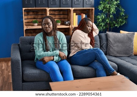African american women friends sitting on sofa with disagreement expression at home Royalty-Free Stock Photo #2289054361