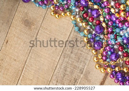 Cheerful Mardi Gras Beads in corner on Rustic Wood Board Background from above with room or space for copy, text, your words.  Horizontal