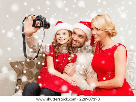 christmas, holidays, technology and people concept - happy family with digital camera taking selfie at home