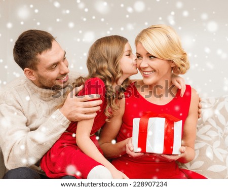 christmas, holidays, happiness and people concept - smiling family with gift box kissing at home