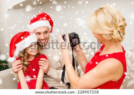 christmas, holidays, technology and people concept - happy family with digital camera taking photo at home