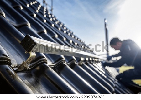 Installation of solar panel support structures on a tiled roof Royalty-Free Stock Photo #2289074965