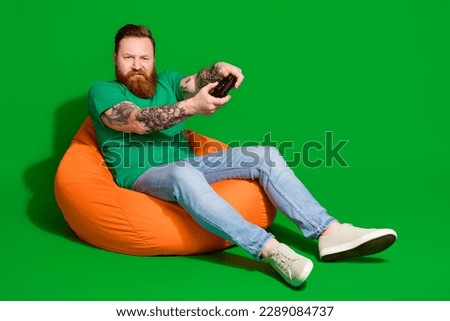 Full length photo of angry upset man wear t-shirt sitting bean bag losing playstation game empty space isolated green color background