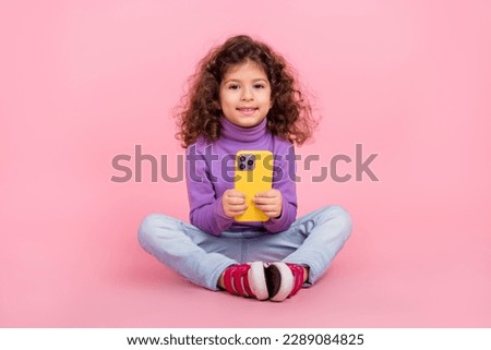 Full length photo of pretty adorable small kid wear violet sweater chatting modern gadget isolated pink color background