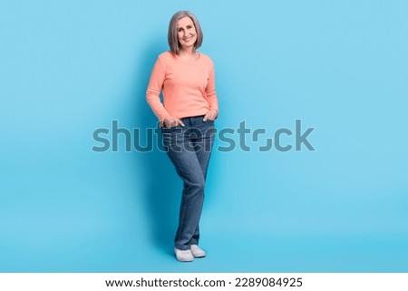 Full body photo of optimistic gorgeous confident business woman hands pockets jeans peachy shirt trendy outfit isolated on blue color background