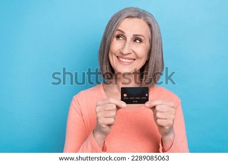 Portrait photo of charming senior woman gray hair hold plastic credit card shopping proposition look empty space isolated on blue color background