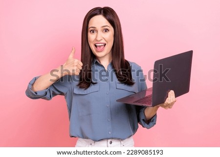 Photo of excited positive glad lady wear grey stylish clothes advise buy modern device thumb up isolated on pink color background