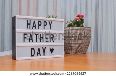 Happy Father Day sign .message on white light box in the wooden table and flowers on that.