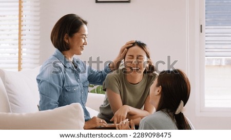 Middle aged mom smile look at two grown up kid child relax hug cuddle stroking with love care warm time. Asia people woman adult older mum parent sitting at home sofa sweet trust moment happy life. Royalty-Free Stock Photo #2289098475