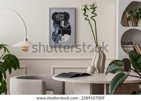 Stylish composition of living room interior with mock up poster frame, round table, gray armchair, beige lamp, books, modern vase with green flowers and personal accessories. Home decor. Template.