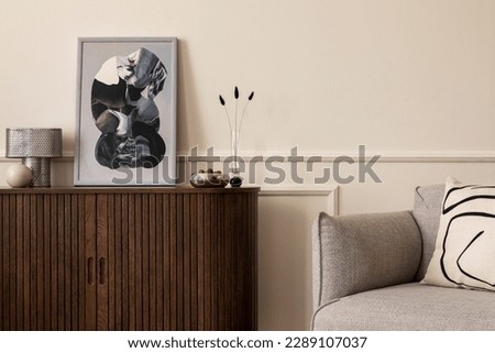 Warm and cozy composition of living room interion with mock up poster frame, gray sofa, patterned pillow, wall with stucco and personal accessories. Home decor. Template. 