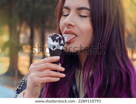 Beautiful woman with delicious ice cream chocolate cookies in waffle cone outdoors spring, closeup