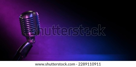Podcast, comedy club or jazz club banner with vintage microphone nad copy space. Old mic in the dark with blue and pink lighting and wide background. Royalty-Free Stock Photo #2289110911