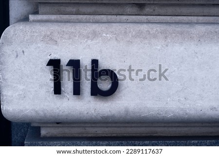 London, England August 20 2021: House numbers. Number 11b. Raised black numerals numbers 11b on a white marble wall.  