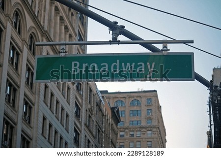 Green big Broadway Street sign hanging on a arch pole in the streets of midtown Manhattan