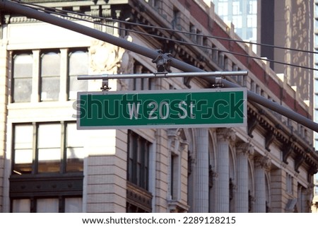 Green big West 20th Street sign hanging on a arch pole in the streets of midtown Manhattan