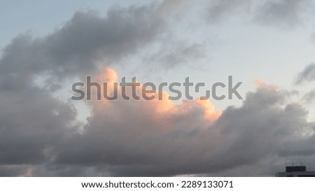 Predominant blue sky picture with clouds and a little orange sunlight                            