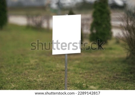 White empty information sign board with mockup space located on lawn with green grass outdoor