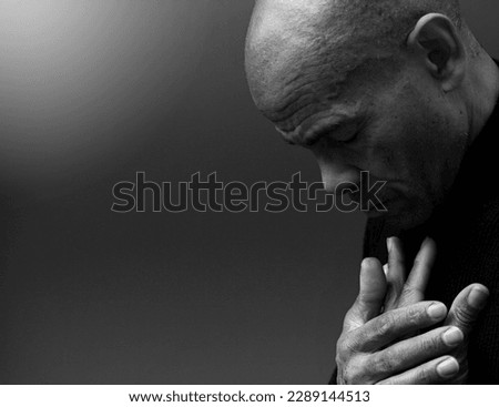 praying to god with hands together Caribbean man praying with black background stock photos stock photo	
