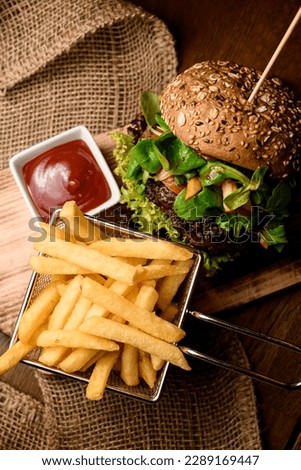 great close-up top view on big tasty double burger and french fries and ketchup on the wooden table Royalty-Free Stock Photo #2289169447