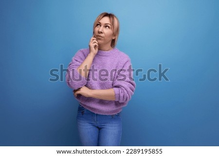 portrait of a pensive sad blonde young woman in a lavender sweater on a bright plain background