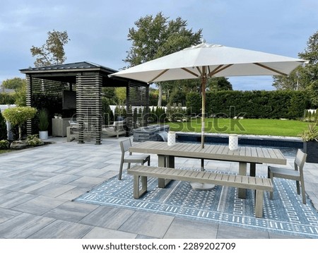 Gorgeous outdoor living backyard patio with pergola, outdoor rug,  tequila bar, dining set, couch, television, pool with waterfall , fire pit and stunning Techo Bloc patio pavers - Inspired by tulum. Royalty-Free Stock Photo #2289202709