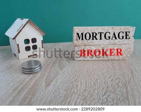 Mortgage broker symbol. Concept words 'Mortgage broker' on brick blocks on a beautiful green backgrounds. Wooden models of house. Business, mortgage broker concept.