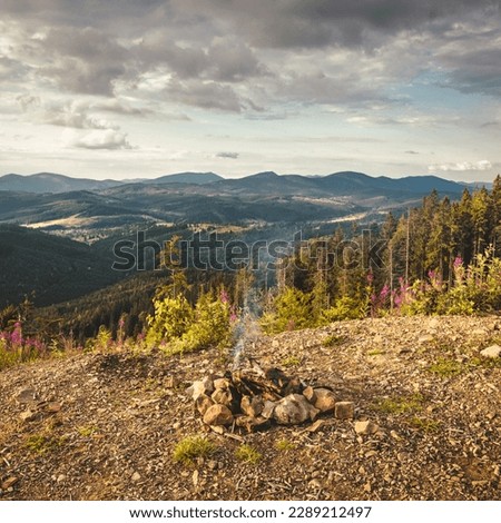 Camp fire on top of a mountain with green forest during a colorful Sunset. Taken on Carpathians Mountians. Ukraine