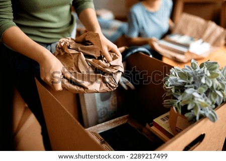 Close up of woman packing her belongings while preparing to move out of her apartment. Royalty-Free Stock Photo #2289217499