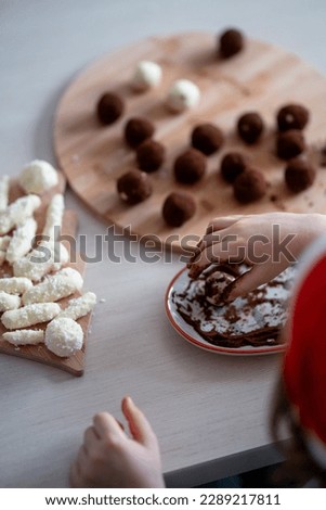 Children's hand sprinkles cocoa homemade sweets while sitting at a table in the kitchen