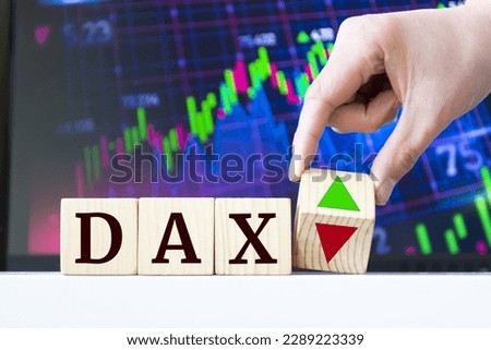 A hand rotates a wooden cube to indicate the fall or rise of the German Stock Index DAX