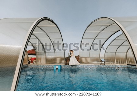 the bride and groom against the background of the sky. Royal wedding concept. the man embraces the bride between the great arches by the pool. Tenderness and calmness.