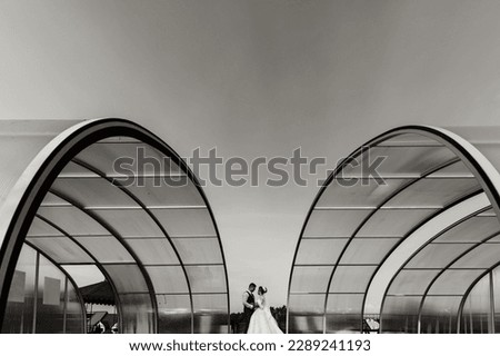 the bride and groom against the background of the sky. Royal wedding concept. the man embraces the bride between large arches. Tenderness and calmness.