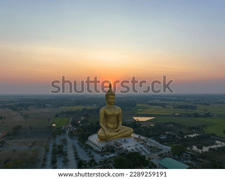 scenery sunset behind the great golden Buddha landmark of Thailand at wat Muang Ang Thong Thailand. 
The largest Buddha statue in the world Surrounded by rice fields.
colorful sky background. 
